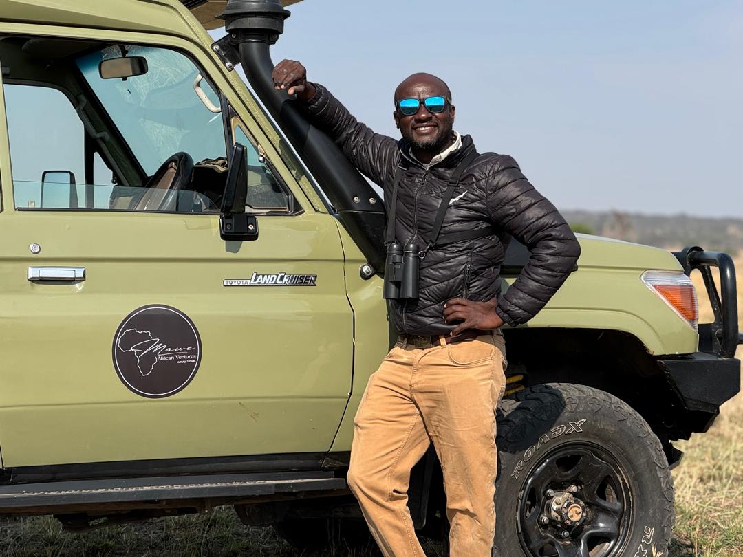 Mawe guide leaning against a safari Land Cruiser with the Mawe logo sticker on the door